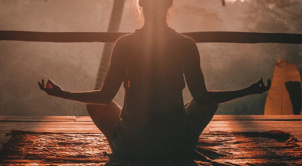 Woman doing yoga meditation on brown parquet flooring