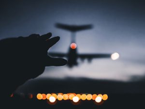 Silhouette photo of a hand reaching out to a landing plane