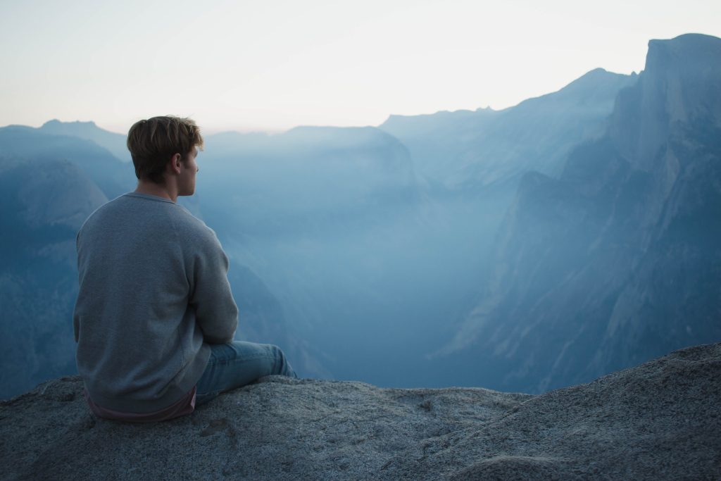 A man in gray shirt sitting on a cliff
