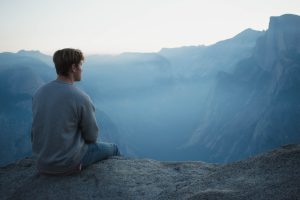 A man in gray shirt sitting on a cliff