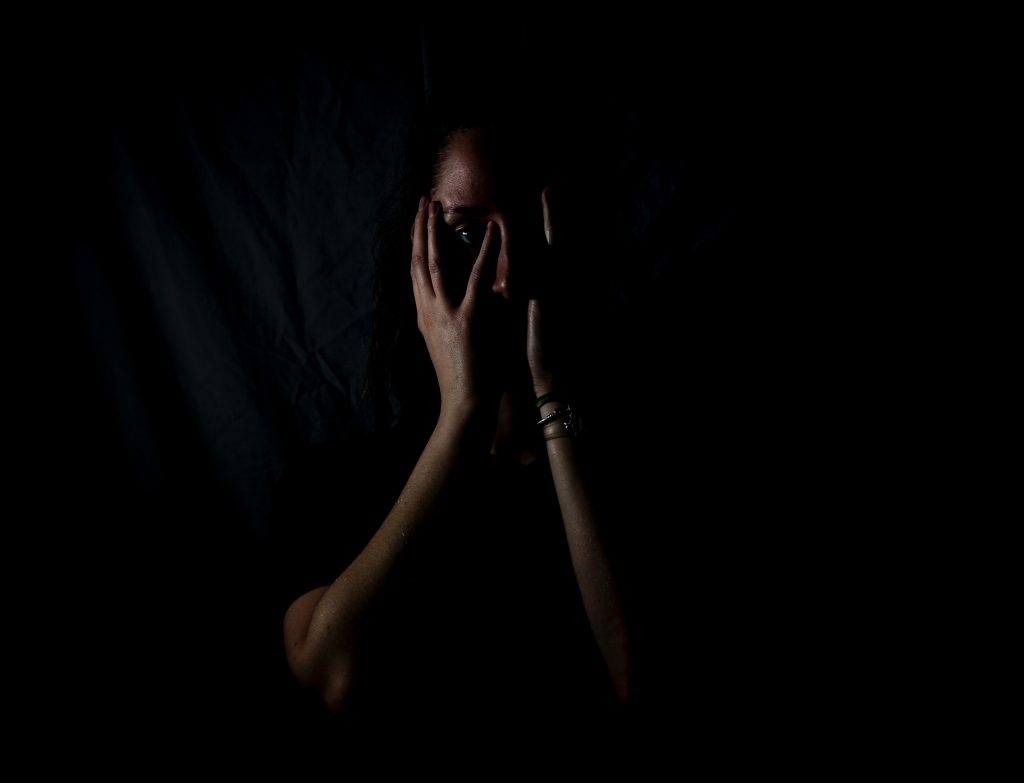 A woman holding her face in a dark room
