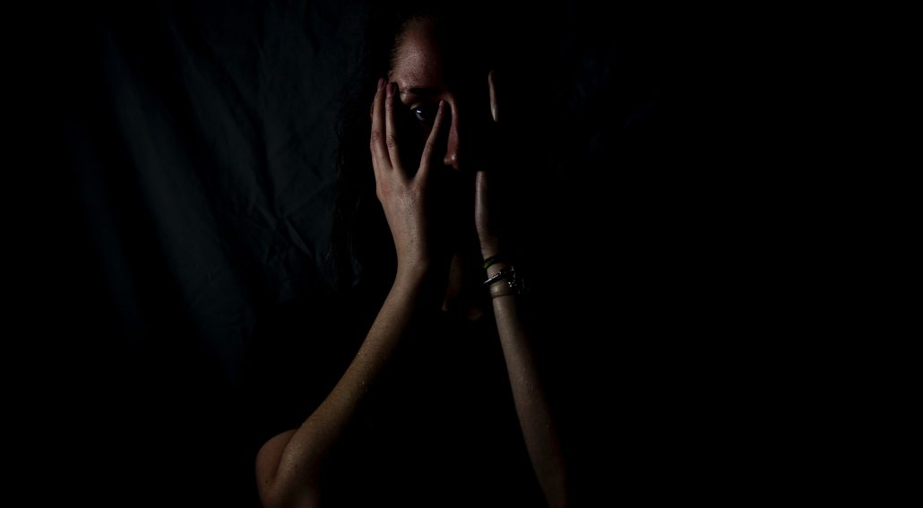 A woman holding her face in a dark room