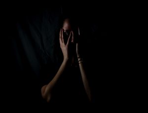 A woman holding her face in a dark room