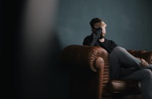Man holding his head while sitting on a sofa