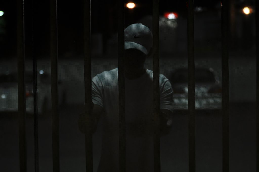 Man on a ballcap inside a cell