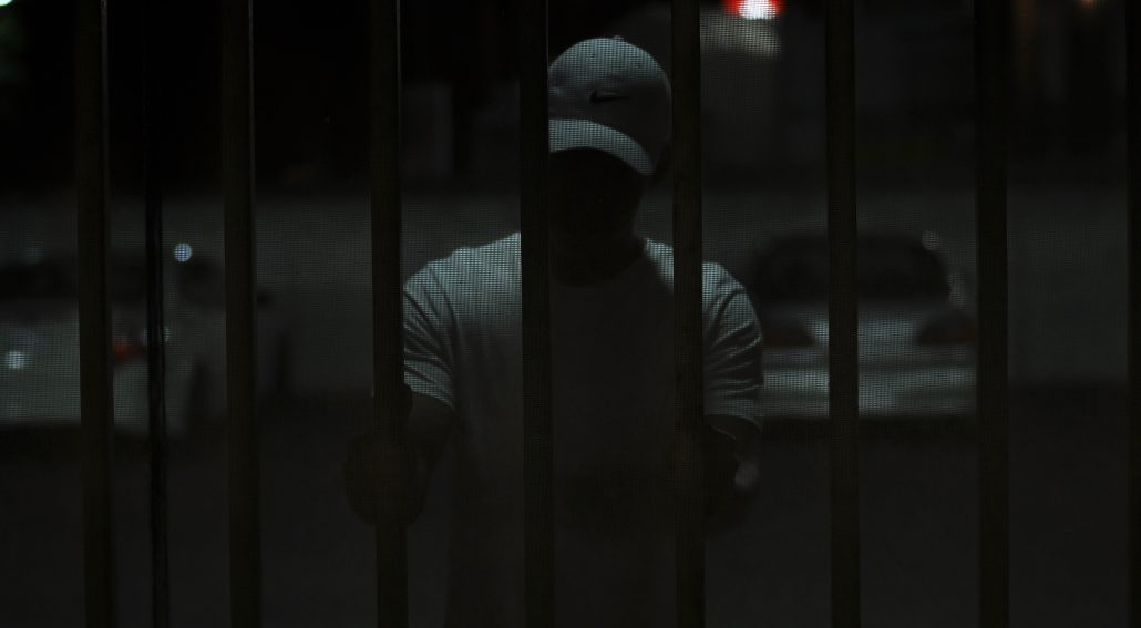 Man on a ballcap inside a cell