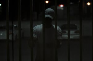 Man on a ballcap inside a cell