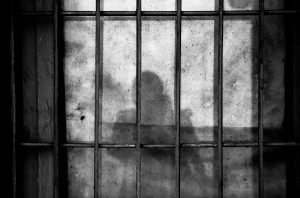Shadow of a person behind bars in a jail cell