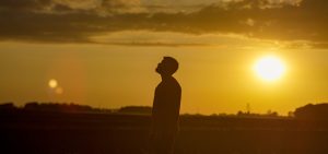 Silhouette of a person standing on a filed during sunset