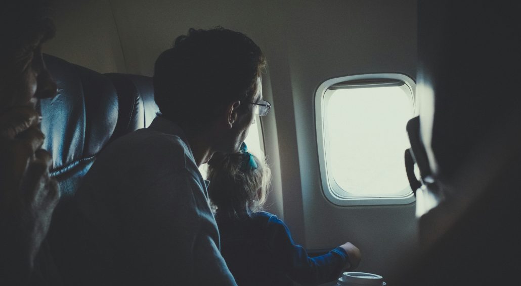 Dad and daughter sitting inside an airplane during daytime