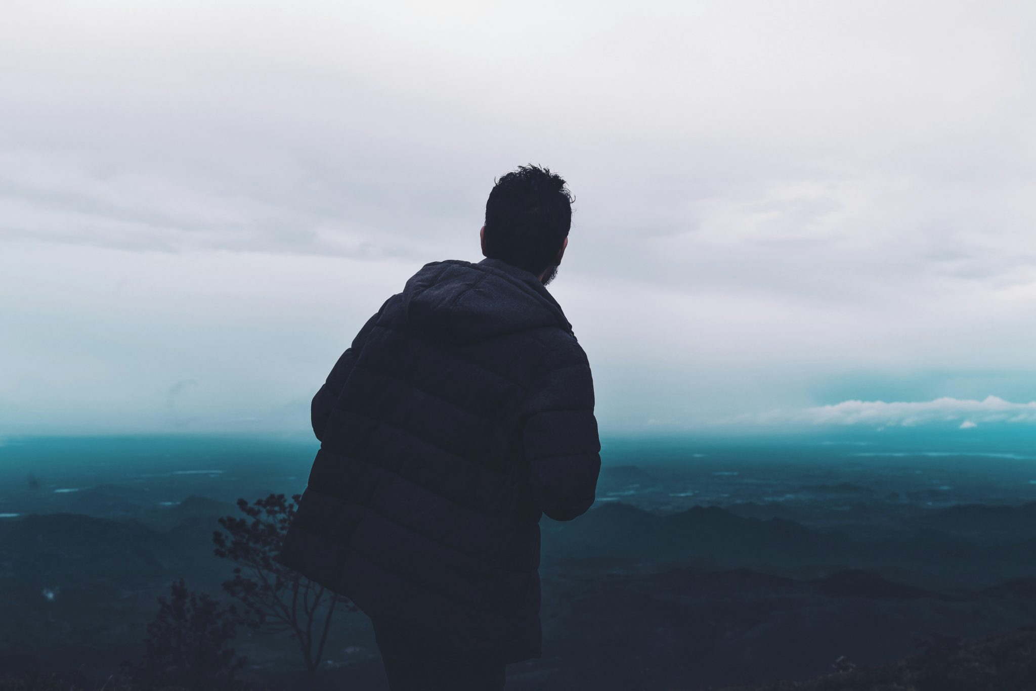 A man standing on top of a mountain staring at the aerial view