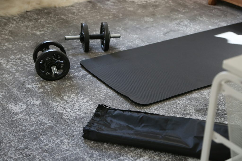 A pair of dumbbells and a black mat on the floor