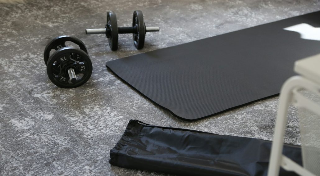 A pair of dumbbells and a black mat on the floor