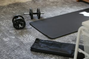 A pair of dumbbells and a black mat on the floor