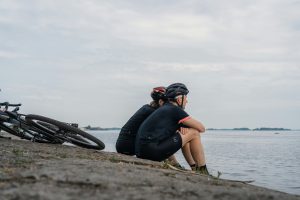 Two bikers sitting on the seashore