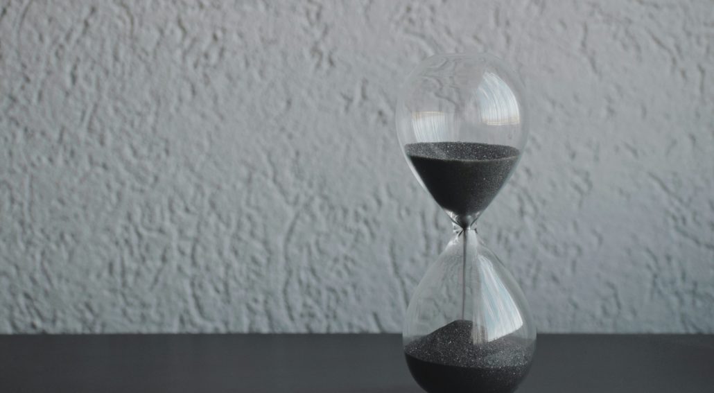 black and white photo of a sand timer on a table