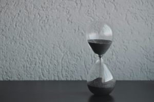 black and white photo of a sand timer on a table