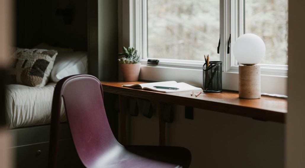 Simple workspace by a window with a notebook, plant, and chair.