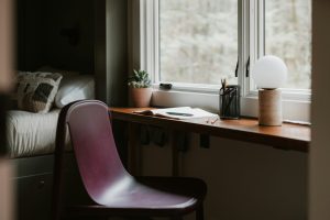 Simple workspace by a window with a notebook, plant, and chair.
