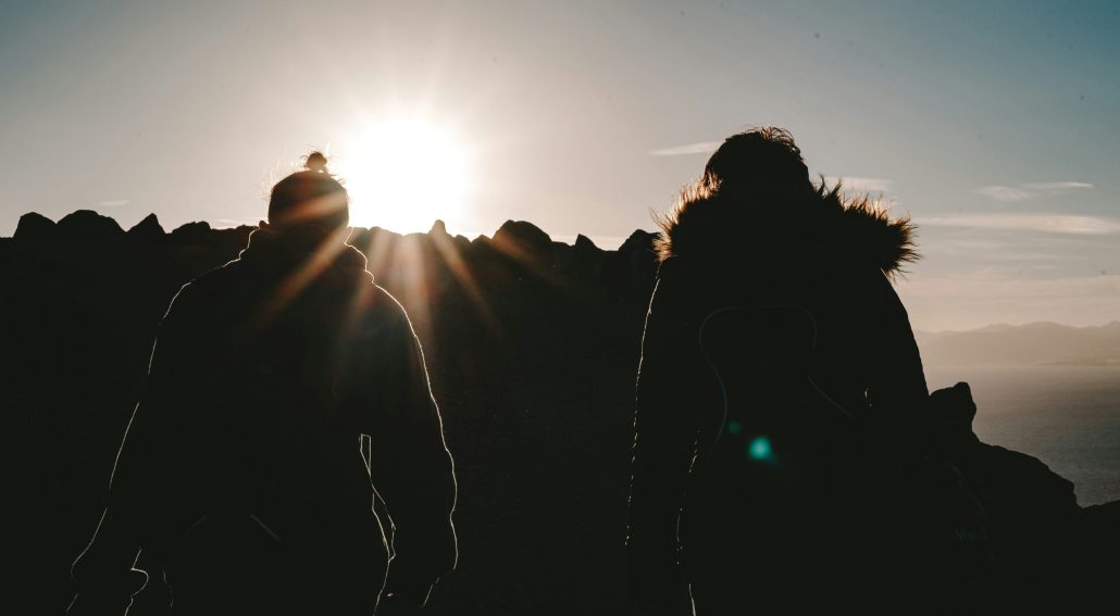 Silhouette of two climbers on a mountain top