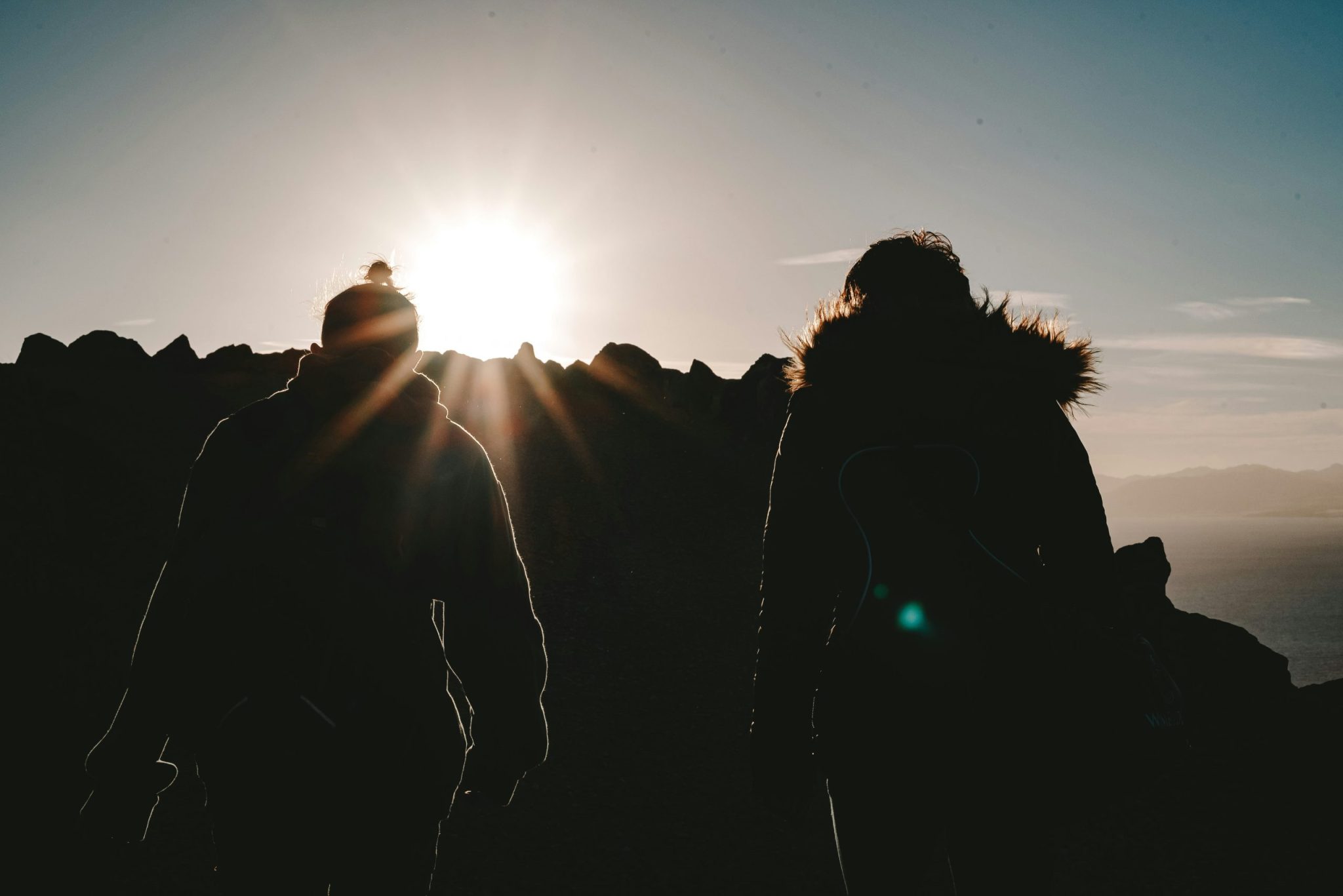 Silhouette of two climbers on a mountain top