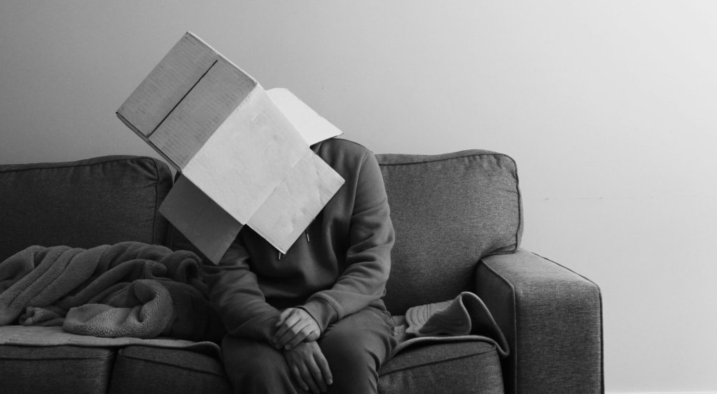 Person sitting on a couch with a cardboard box on their head