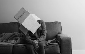 Person sitting on a couch with a cardboard box on their head