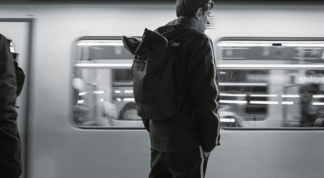 Person waiting by a moving train in black and white
