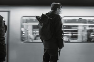 Person waiting by a moving train in black and white
