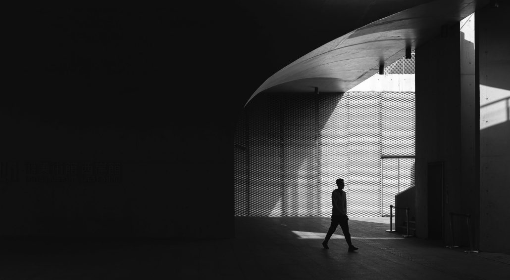 Silhouette of a person walking through an architectural space with light and shadow