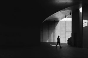 Silhouette of a person walking through an architectural space with light and shadow