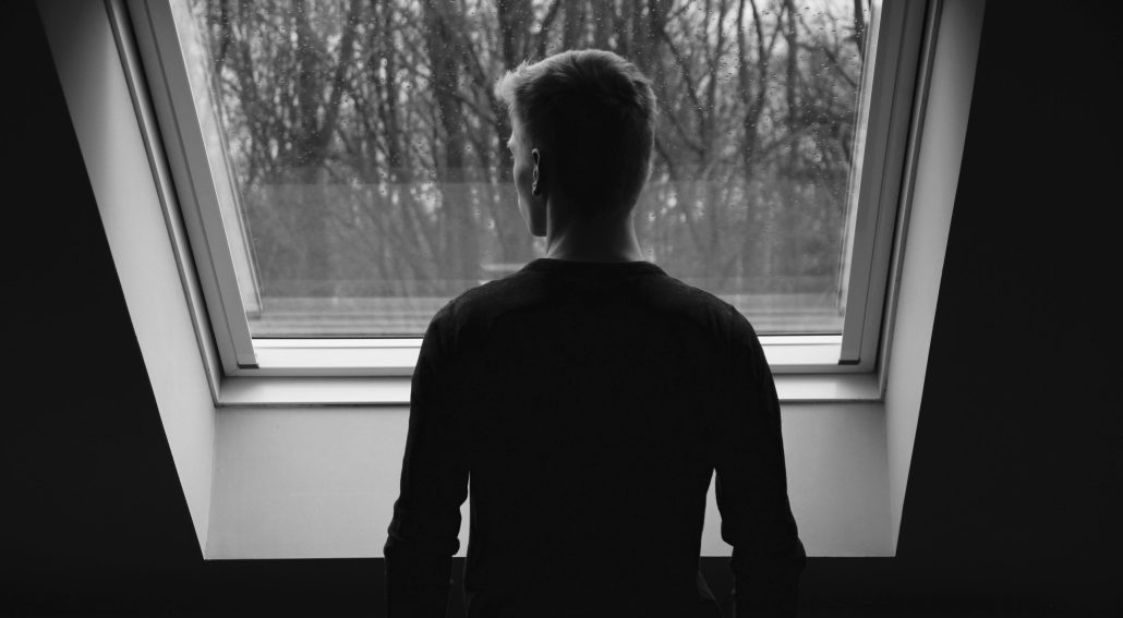 Silhouette of a man staring outside a window