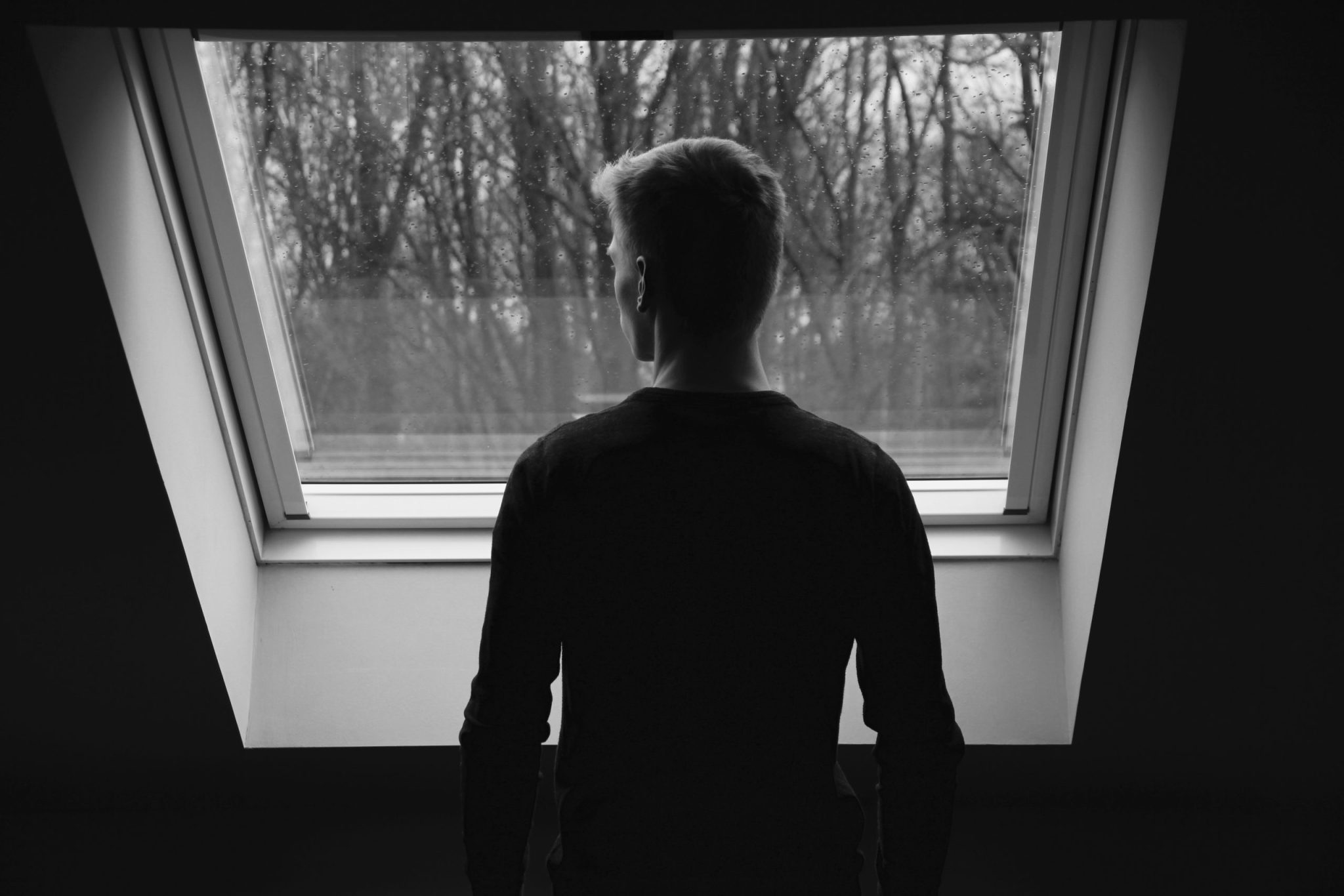 Silhouette of a man staring outside a window
