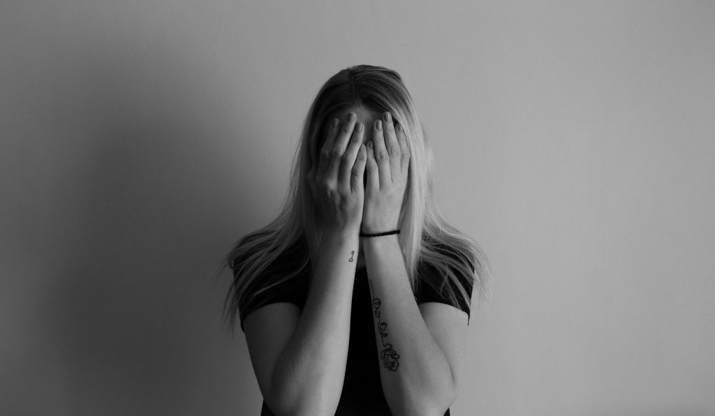 Black and white photo of a woman with her hands on her face
