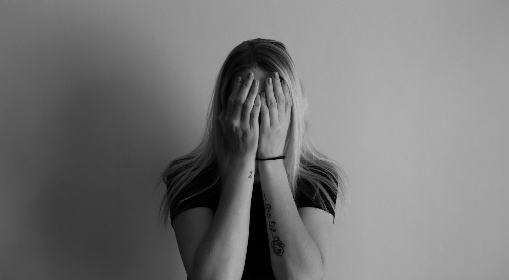 Black and white photo of a woman with her hands on her face