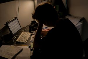 Person sitting at a desk with their head resting on their hand while working