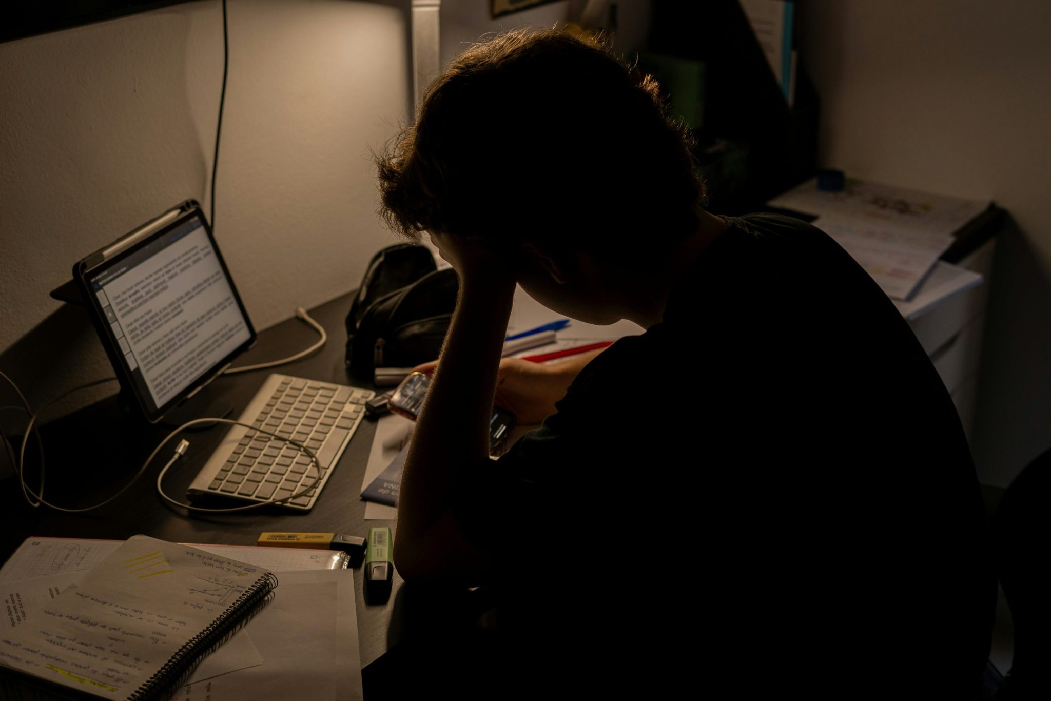 Person sitting at a desk with their head resting on their hand while working