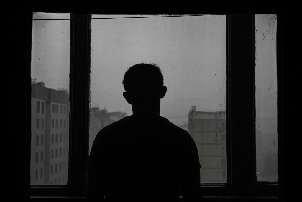 Silhouette of a person standing and looking out a large window