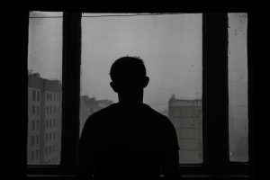 Silhouette of a person standing and looking out a large window