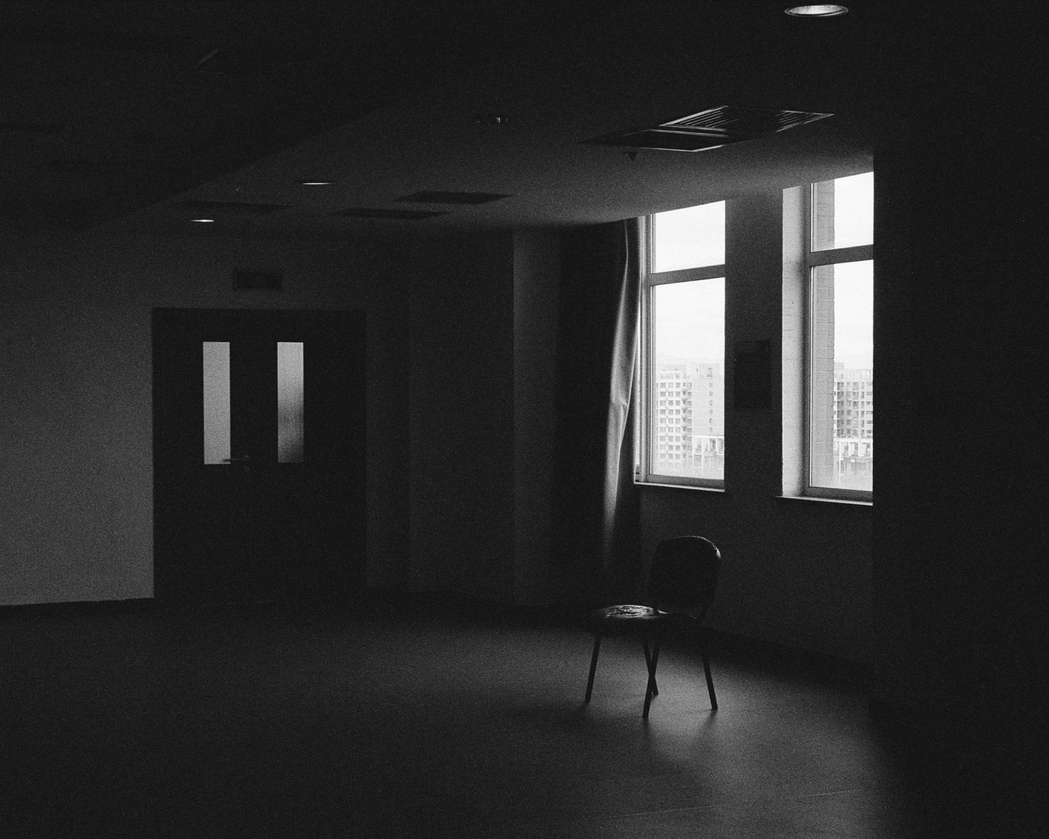 A lone chair in a dimly lit room with windows
