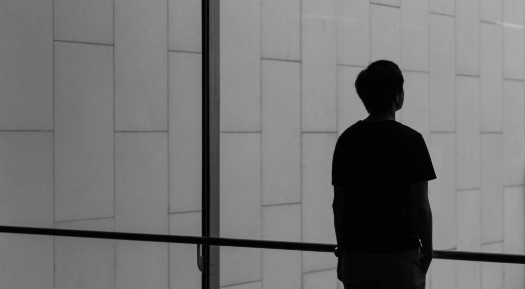 Silhouette of a person standing near a wide glass window