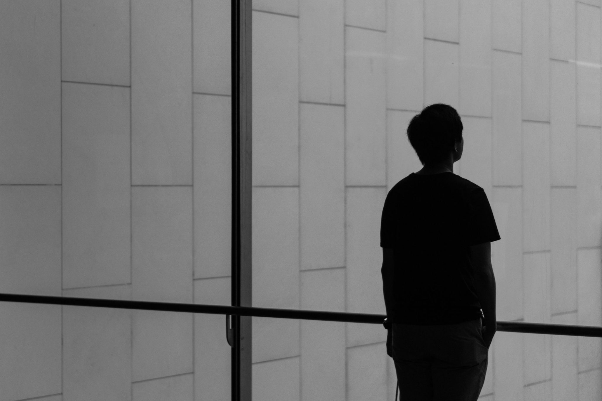 Silhouette of a person standing near a wide glass window