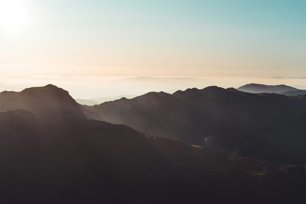 Sunlight over layered mountain ridges at sunrise