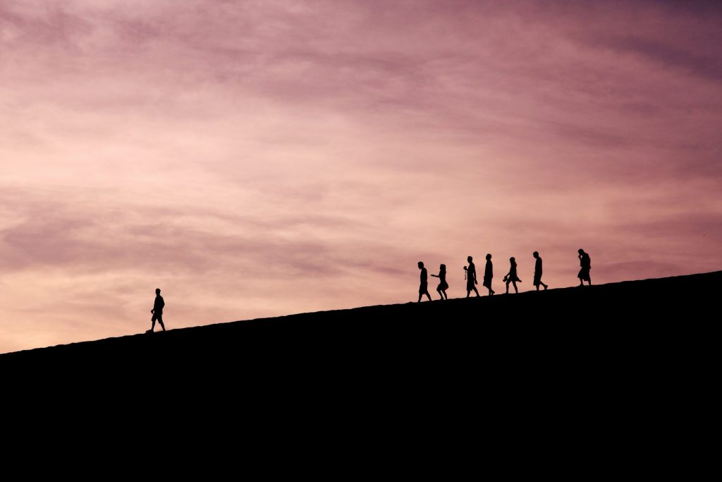 Silhouette of people walking along a ridge at sunset