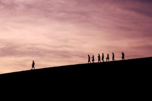 Silhouette of people walking along a ridge at sunset