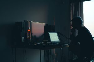 Silhouette of a man inside his room working on a computer