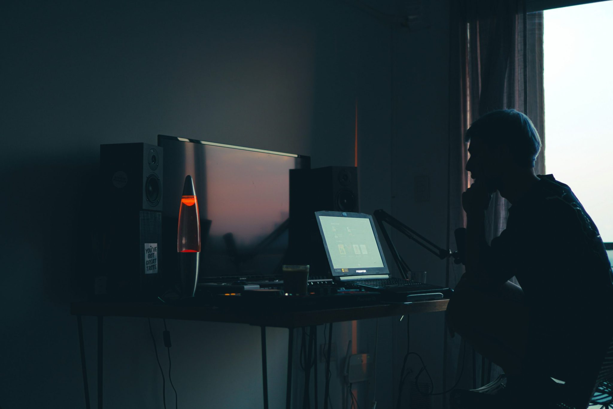 Silhouette of a man inside his room working on a computer