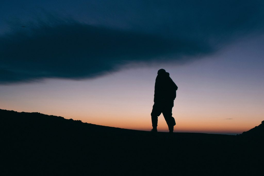 Silhouette of a man on top of a mountain at dusk