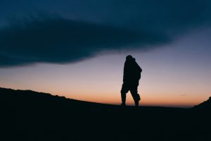 Silhouette of a man on top of a mountain at dusk