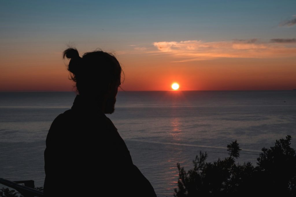 Silhouette of a man watching the sun set over the ocean